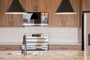 A modern kitchen with a stainless steel oven and wooden cabinets. at Townhomes at Preserve, Rogers, MN